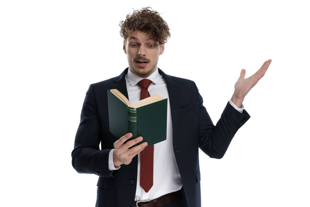 Позитивный бизнесмен, читающий и объясняющий книгу в костюме и стоящий на белом фоне студии
 - Фото, изображение