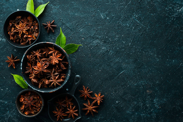 Anise stars in bowls on black stone background. Badian - Indian spices. Top view. - Foto, Imagen