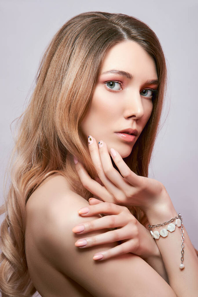 Beauty portrait of a woman with long hair, earrings in her ears and expensive jewelry on her hands - Фото, изображение