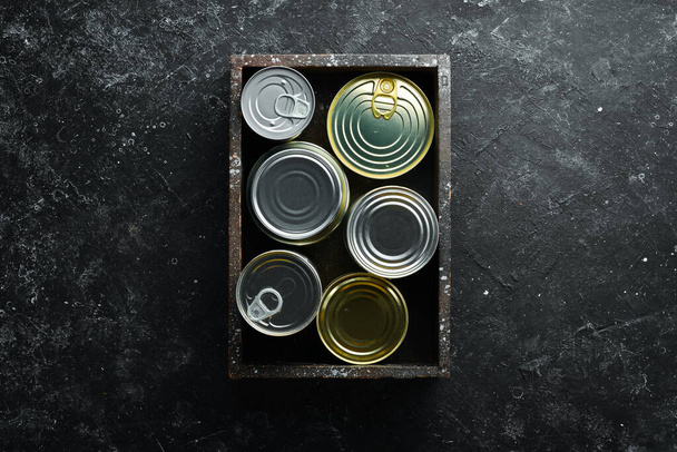 Set of tin cans with food in wooden box. Top view. Free space for your text. - Fotoğraf, Görsel