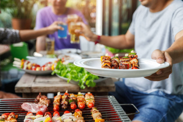 Человек с тарелкой для барбекю на вечеринке между друзьями. Еда, люди и семейное время
. - Фото, изображение
