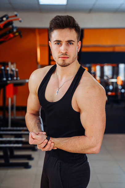 Muscular model young man in the gym. Fashion portrait of strong brutal guy. Male flexing his muscles. Sport workout bodybuilding concept. - 写真・画像