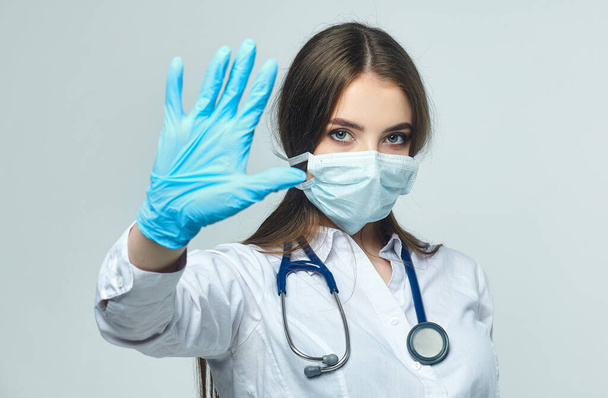 Covid19, coronavirus, a concept of healthcare and doctors. Portrait of a female doctor who shows a stop gesture! puts on a medical mask to prevent infection with the virus - Photo, image