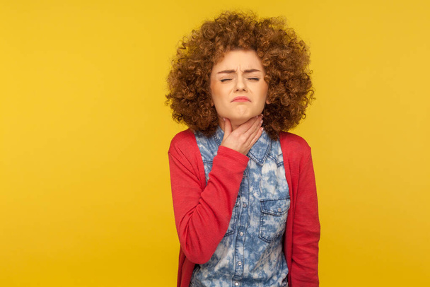 Flu symptoms, respiratory disease. Portrait of unhealthy woman wincing in pain and touching painful neck, suffering sore throat, larynx inflammation. indoor studio shot isolated on yellow background - Фото, зображення