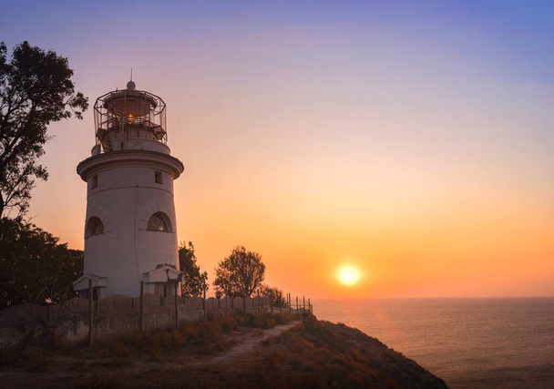 Shipping lighthouse on the seashore at sunrise - Foto, imagen
