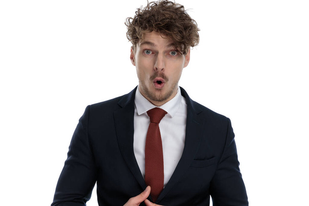 Surprised businessman gasping while wearing suit and standing on white studio background - Photo, Image