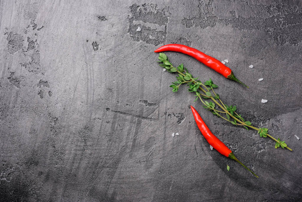 Chili pepper and fresh thyme on a gray concrete background, top view - Photo, image