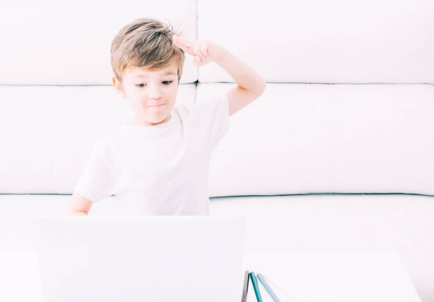 Un jeune enfant accueille l'ordinateur pendant qu'il fait ses devoirs à la maison
. - Photo, image