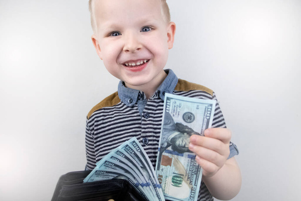Blonďatý chlapec drží v rukou dolary. Dítě se raduje z toho, že má kapesné. Koncepce školení finanční gramotnosti - Fotografie, Obrázek