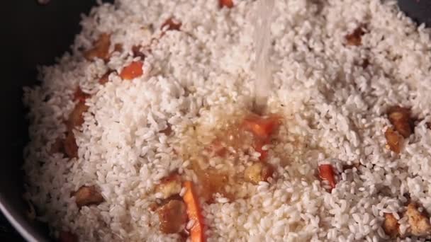 Koken van pilaf close-up. Kook rijst, knoflookvarkensvlees en gesneden wortel. - Video