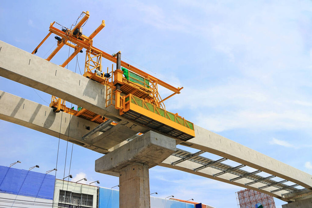 Máquina de elevação móvel trabalhando em vigas de concreto para o trem do céu em construção
 - Foto, Imagem