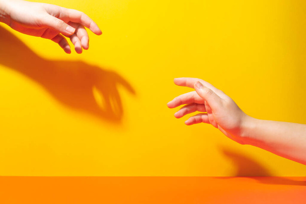 İki el parmaklarıyla birbirine uzanıyor. Gölgeler ve sert ışık - Fotoğraf, Görsel
