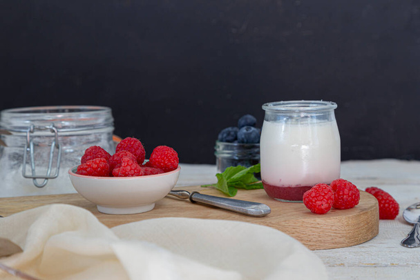 Healthy morning breakfast with fresh yogurt in clear glass and berries on a wooden board. Healthy life concept. - Фото, изображение