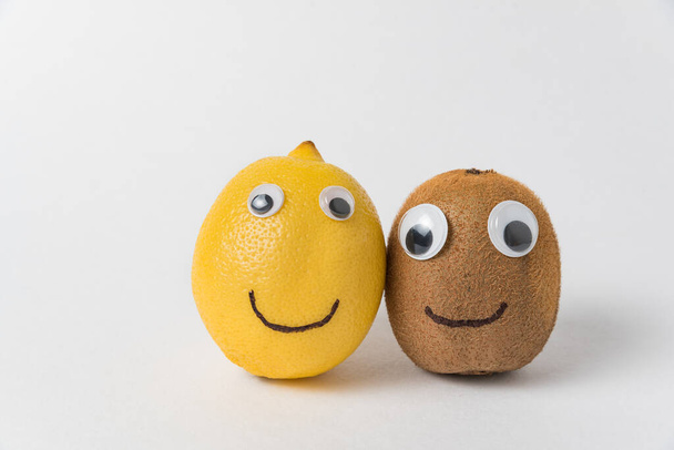 Kiwi und Zitrone mit göttlichen Augen und einem Lächeln auf weißem Hintergrund. Freundschaftskonzept. - Foto, Bild