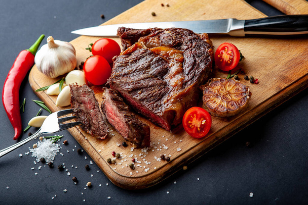 Fresh juicy ribeye steak with a set of spices on a cutting board - Fotó, kép