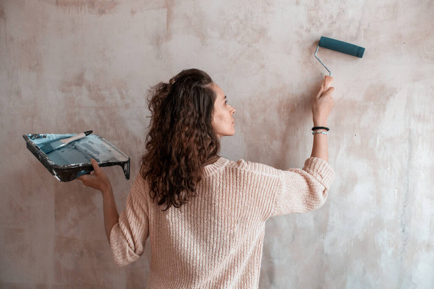 Girl with roller and paint to paint a textured wall - Foto, Bild