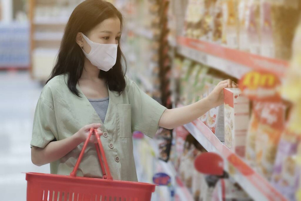 Asian women and surgical mask shopping some food in supermarket, covid-19 crisis - Foto, Imagen