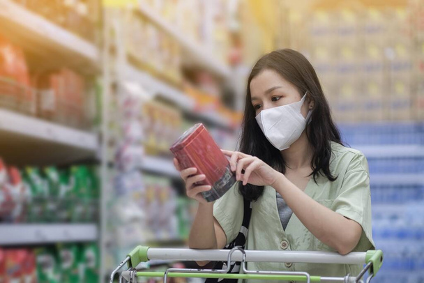 Азіатські жінки і хірургічна маска закупляють трохи їжі в супермаркеті, криза Конід-19 - Фото, зображення