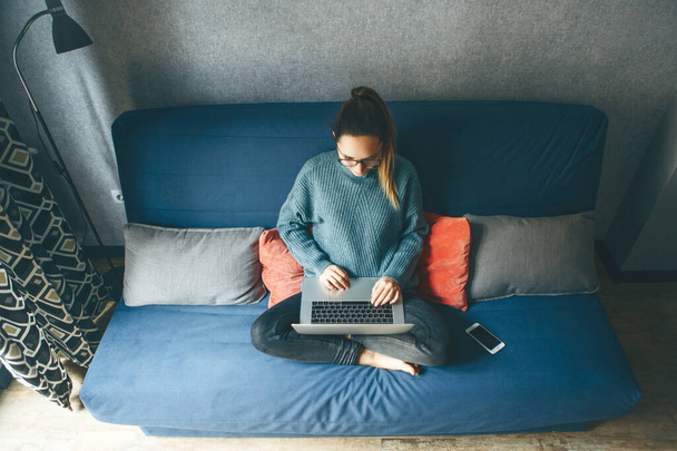 Lány dolgozik laptop otthonról vagy diák tanul otthonról vagy szabadúszó. Vagy videót néz, vagy netezik. - Fotó, kép