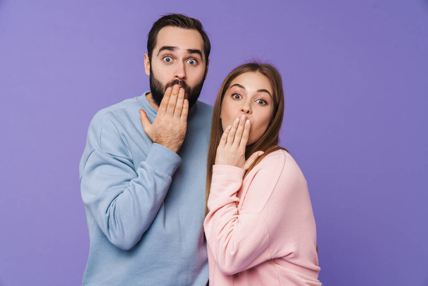 Photo of a shocked young loving couple isolated over purple background. - Φωτογραφία, εικόνα