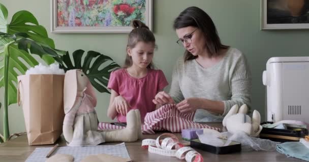 Happy mother and daughter sewing together toy bunny doll at home - Imágenes, Vídeo