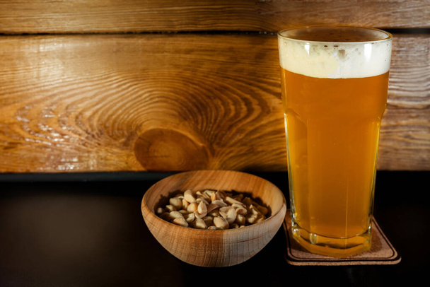 Premium ambachtelijk bierglas met pistaches op houten ondergrond - Foto, afbeelding