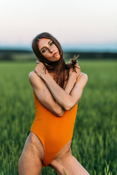 Beautiful girl in a bright bodysuit, Brunette with long hair, alone in the forest, evening light through the trees. greens, the sun. - Foto, Bild