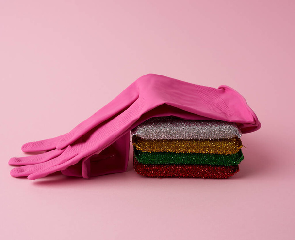 різнокольорова кухонна губка, гумові рожеві рукавички на рожевому фоні, набір предметів для прибирання
 - Фото, зображення