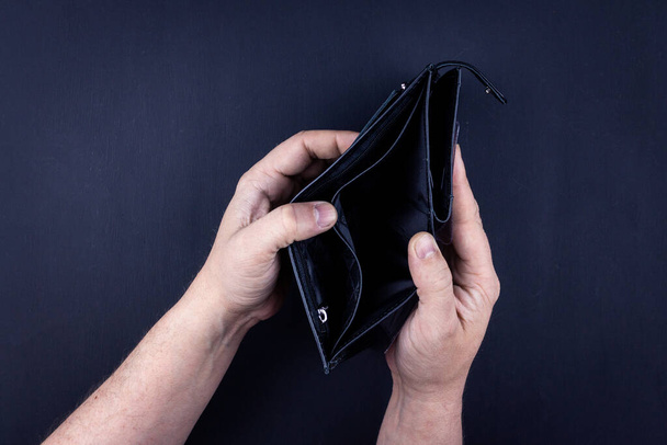 men's hands hold an empty purse. A wallet with little money in it. The concept of poverty and bankruptcy - Foto, Imagen