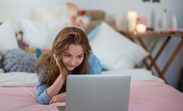 Beautiful happy young girl with laptop sitting and smiling, online dating concept. - Foto, Bild