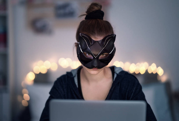 Young girl with cat mask and laptop sitting, online dating and abuse concept. - Фото, зображення