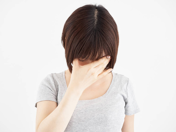 Een vrouw drukt haar pijnlijke ogen tegen een witte achtergrond - Foto, afbeelding