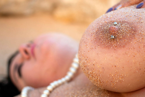 красива чуттєва жінка оголена позує в природі, біля берегової лінії на піску
. - Фото, зображення