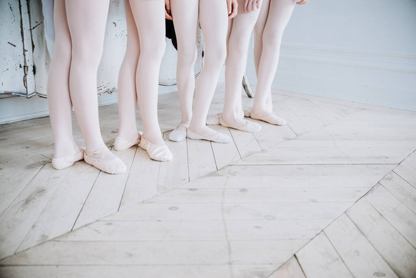 Balettitanssijan jalat studion lattialla. Teini-ikäinen tanssija laittaa balettikengät jalkaan. Eleganssi ja tasapaino käsite ylhäältä horisontaalinen näkymä
 - Valokuva, kuva