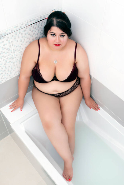 femme en lingerie rouge foncé sensuelle sur une baignoire laiteuse
. - Photo, image
