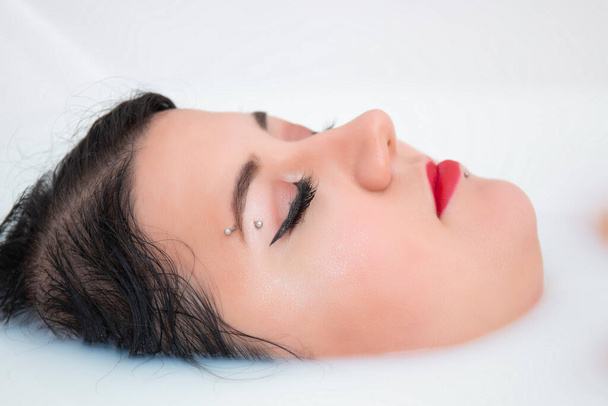 woman face closeup half submerged on milky bathtub. - Φωτογραφία, εικόνα