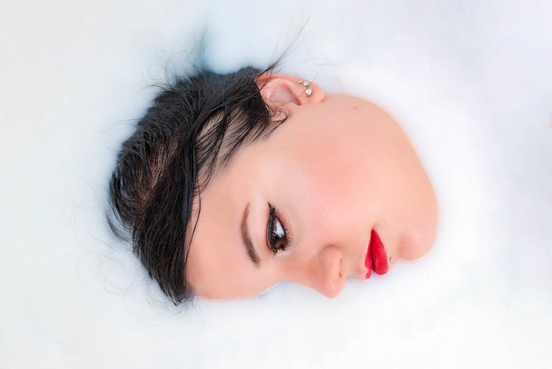 woman face closeup half submerged on milky bathtub. - Foto, Imagem