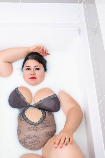woman wearing sensual lingerie on a milky bathtub. - Photo, Image