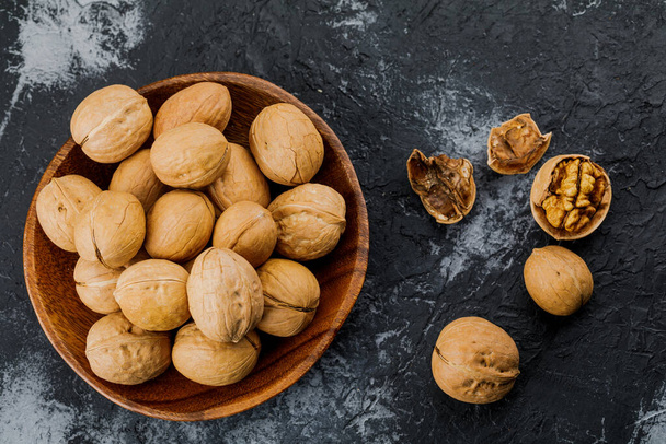 plate with some raw walnuts and peel on dark background. - Photo, Image