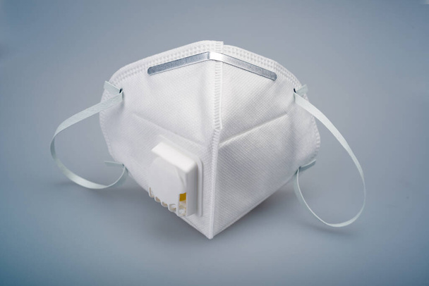  Una máscara N95 blanca con una válvula de respiración sobre un fondo gris
 - Foto, Imagen