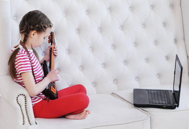  Cours en ligne de guitare à la maison à l'aide d'un ordinateur portable. Concept d'enseignement à domicile
. - Photo, image