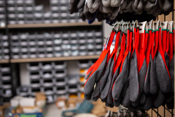 Protected red gloves at construction equipment store. Copy Space. - Photo, Image