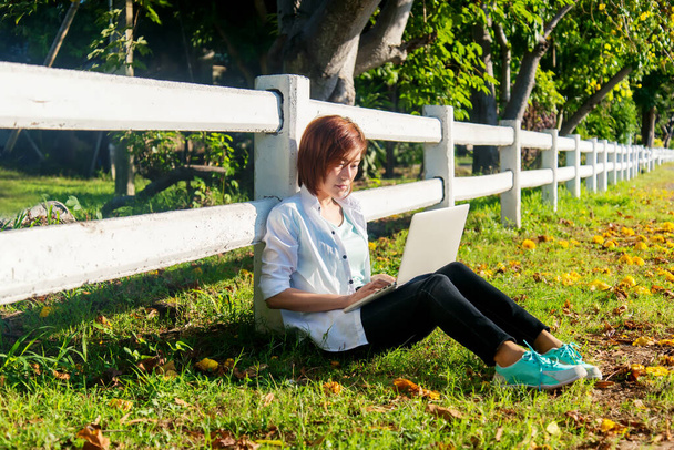 Lifestyle people freelance work from home with laptop on the grass in nature park outdoors.  Young Woman stay home and resting in summer vacations.  - 写真・画像