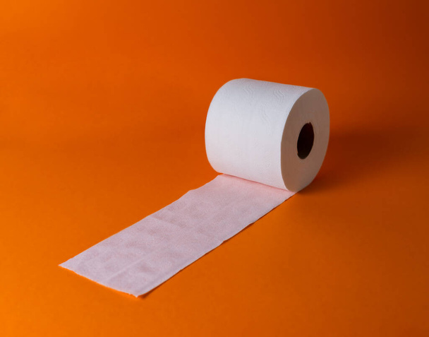 Blick auf eine weiße Toilettenpapierrolle auf orangefarbenem Hintergrund und Kopierraum - Foto, Bild