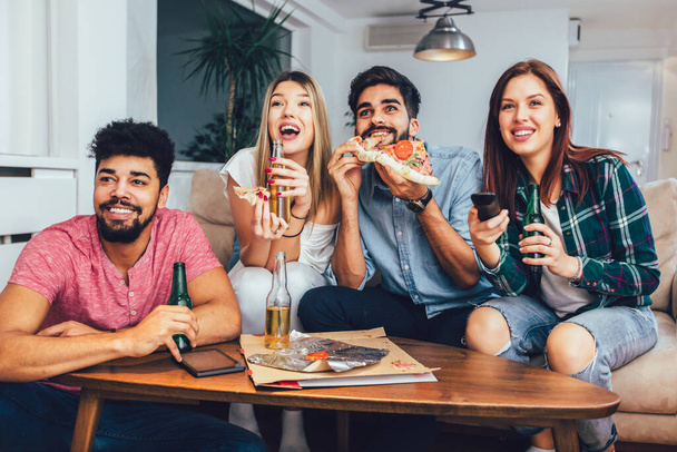 Постріл друзів, що їдять піцу, п'ють пиво і дивиться телевізор
. - Фото, зображення