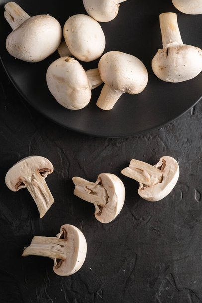 Champignon funghi cibo sano su piatto nero su sfondo nero scuro testurizzato, vista dall'alto - Foto, immagini