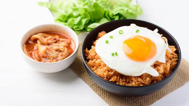Kimchi fried rice with fried egg on top in a bowl and fresh kimchi cabbage, Korean food - Photo, Image