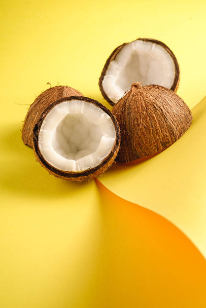 Frutas de coco sobre papel dobrado amarelo fundo liso, abstrato alimento conceito tropical, vista de ângulo
 - Foto, Imagem