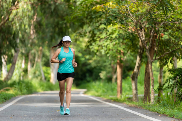 Femme saine course de jogging et d'entraînement sur la route en plein air. Asiatique coureur personnes gymnase d'exercice avec séance de remise en forme, arrière-plan de parc naturel. Concept de mode de vie sain. - Photo, image