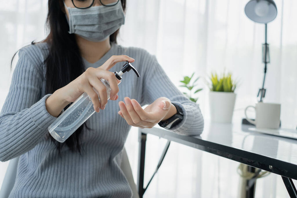 Asijský muž nosí masku čerpadlo ruční gel alkohol čištění dezinfekční práce z domova s notebookem zabránit šíření koronaviru karanténní pracoviště s ochranným pobytu doma. - Fotografie, Obrázek